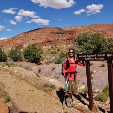 Woman with backpack stands next to sign that says Arizona National Scenic Trail, Buckskin Passage